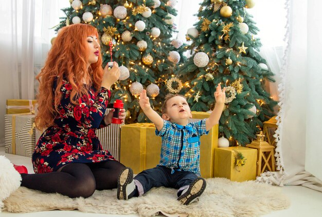 Feliz madre y su hijo rodeados de adornos navideños