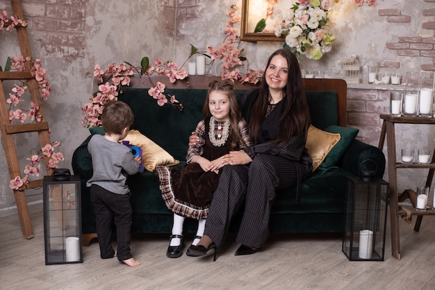 Feliz madre y su pequeña hija e hijo, feliz familia sonriente en el sofá en casa