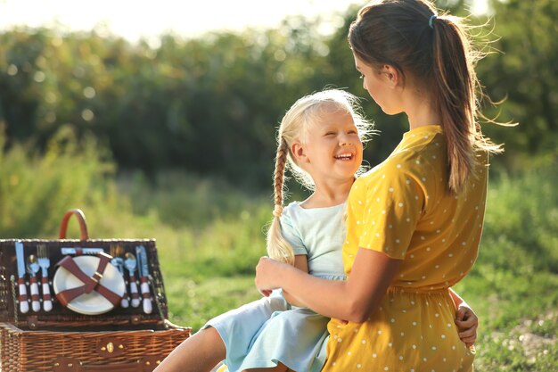 Feliz madre y su pequeña hija en un picnic en el parque