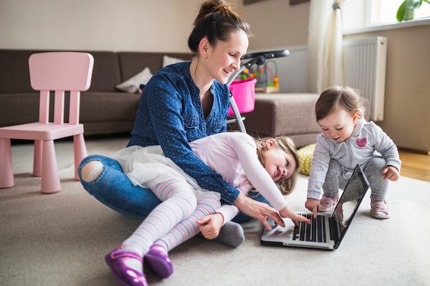 Feliz madre con sus hijos trabajando en la computadora portátil