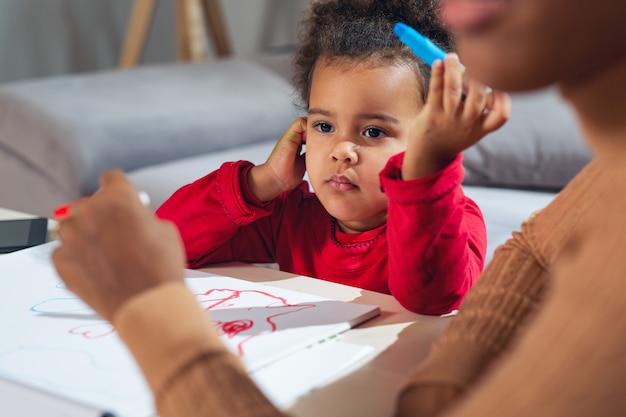 Feliz mãe afro-americana, ajudando a filha na coloração