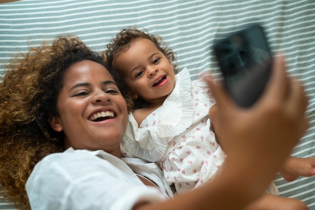 Feliz mãe afro-americana brincando com sua garota no quarto em casa