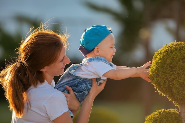 Feliz mãe amorosa segurando o garotinho em seus braços no parque de verão