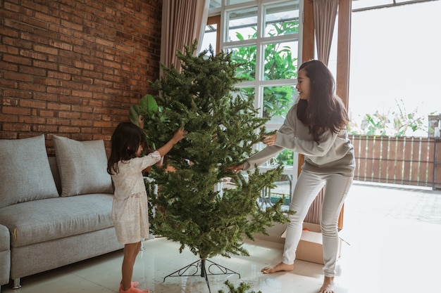 Feliz mãe asiática e filha decorando a árvore de natal