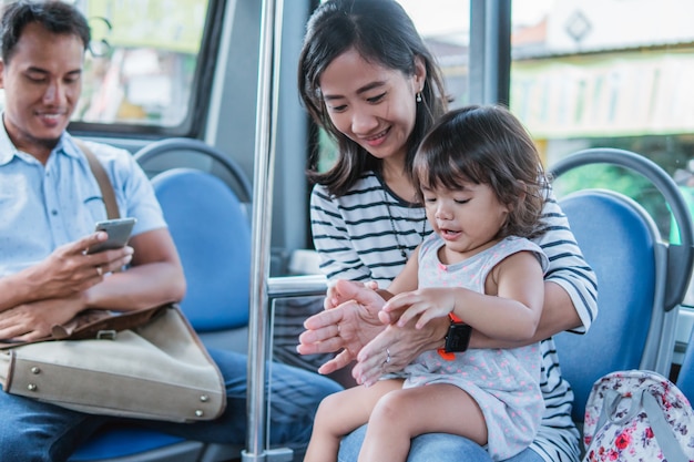 Feliz mãe asiática levando a filha no transporte público