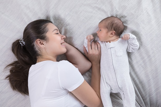 Feliz mãe calma feliz e bebê recém-nascido descansando juntos na cama