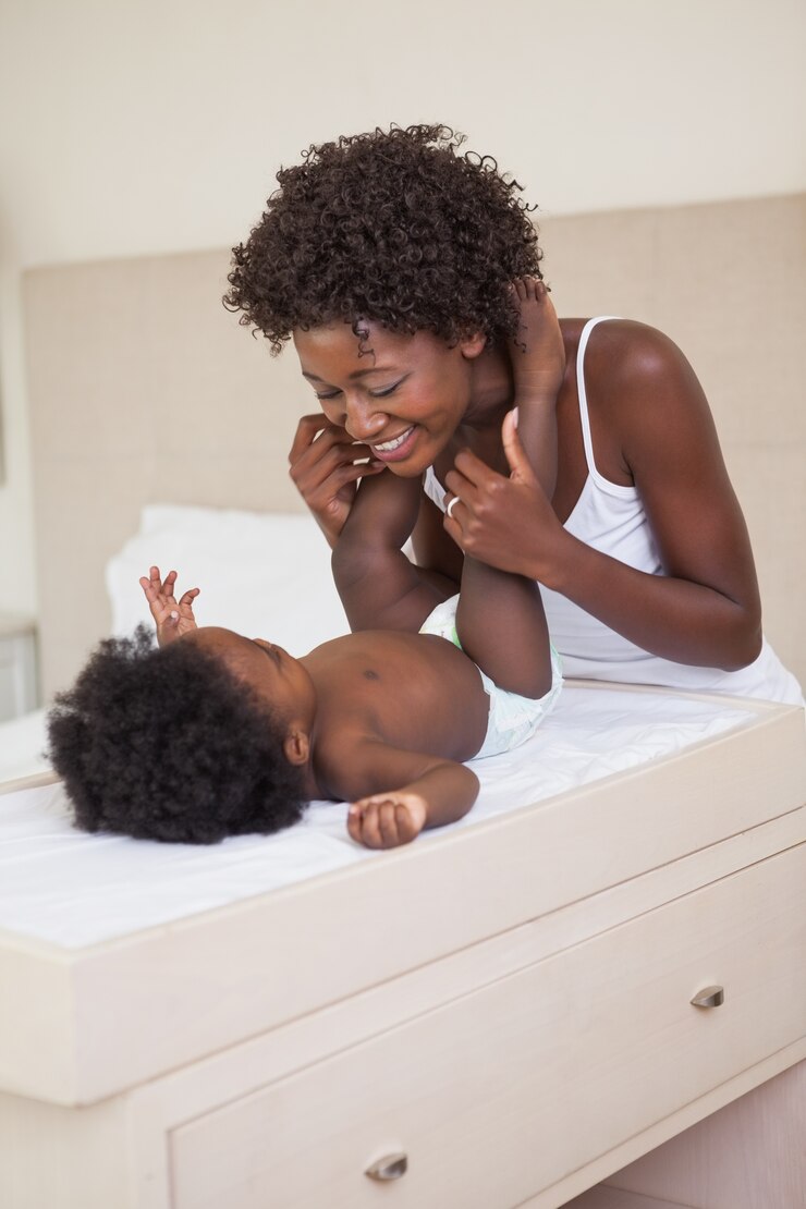 Foto feliz mãe com bebé na mesa de mudança