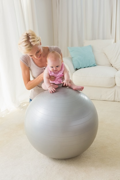 Feliz mãe com sua menina na bola do exercício