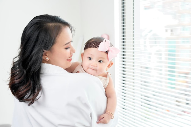 Feliz mãe de família amorosa brincando com seu bebê no quarto