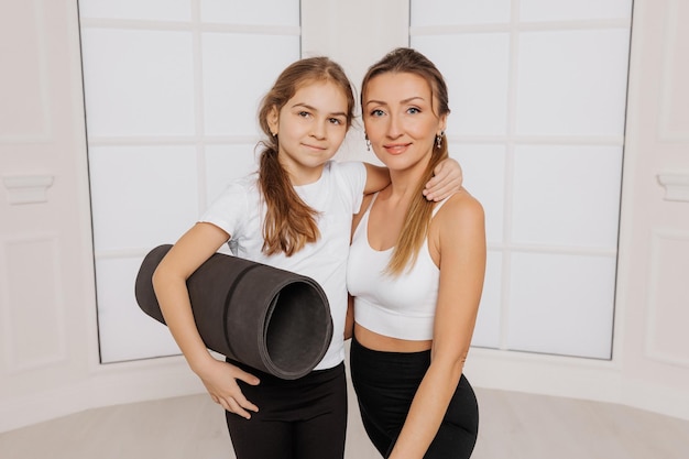 Feliz mãe e filha abraçando em roupas esportivas na academia