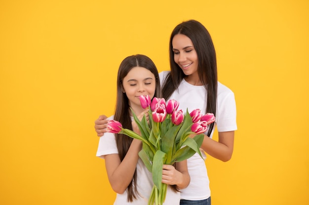 Feliz mãe e filha com buquê de tulipa em fundo amarelo