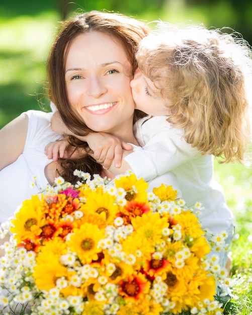 Foto feliz mãe e filha com um grande buquê de flores da primavera se divertindo ao ar livre