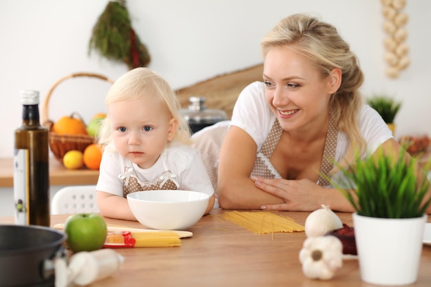 Feliz mãe e filha cozinhando na cozinha. Passar o tempo todos juntos, conceito de diversão em família.