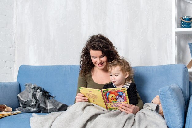 Feliz mãe e filha da família lê um livro pela manhã em casa