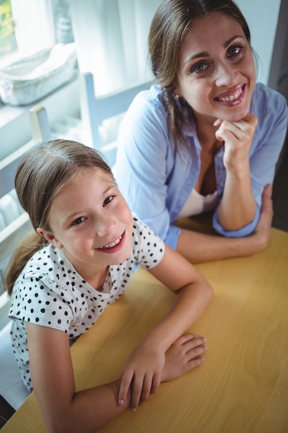 Feliz mãe e filha encostada na mesa