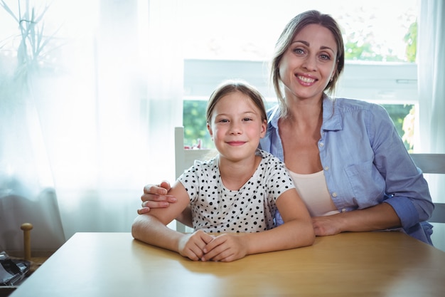 Feliz mãe e filha encostada na mesa