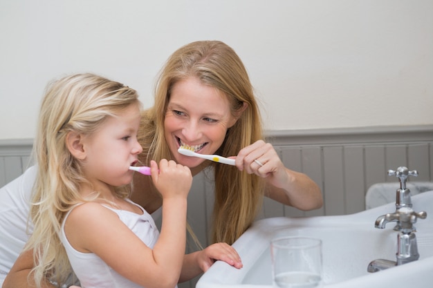 Feliz mãe e filha escovando os dentes