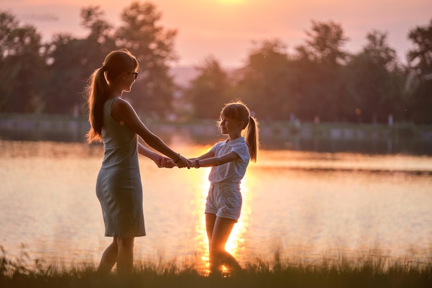 Feliz mãe e filha juntos de mãos dadas aproveitando o tempo no parque de verão à noite. Conceito de amor e relacionamento familiar.