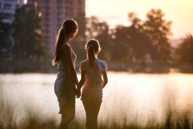 Feliz mãe e filha juntos olhando para o prédio em construção sonhando com sua futura casa ao pôr do sol Amor familiar e conceito de relacionamento