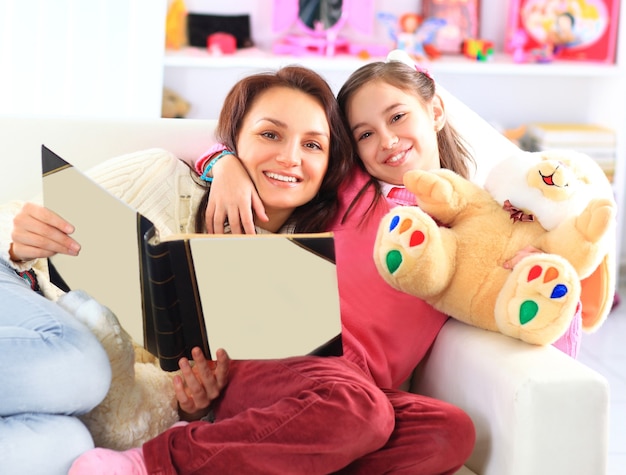 Feliz mãe e filha lendo um livro juntas