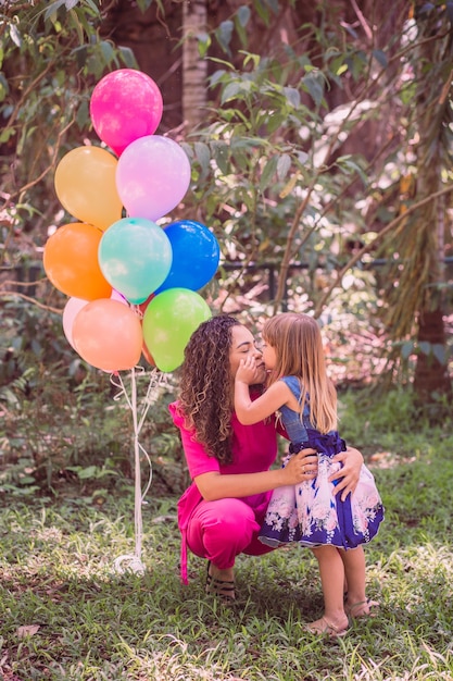 Feliz mãe e filha no parque com balões.