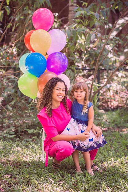 Feliz mãe e filha no parque com balões.