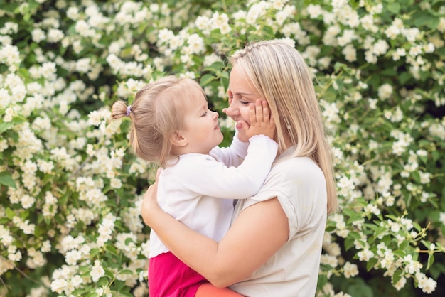 Feliz mãe e filha no parque em um dia ensolarado ao pôr do sol Mãe e filho ao ar livre Conceito de ternura família mãe solteira flores sorrisos abraços harmonia de saúde mental