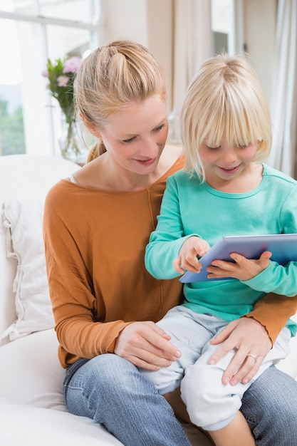 Feliz mãe e filha no sofá usando o tablet