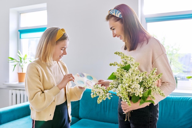 Feliz mãe e filha parabenizando com buquê de flores e cartão