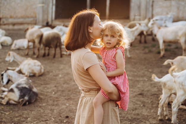 Feliz mãe e filha passam um tempo em uma fazenda ecológica entre cabras.