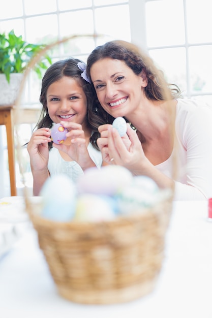 Feliz mãe e filha pintando ovos de páscoa