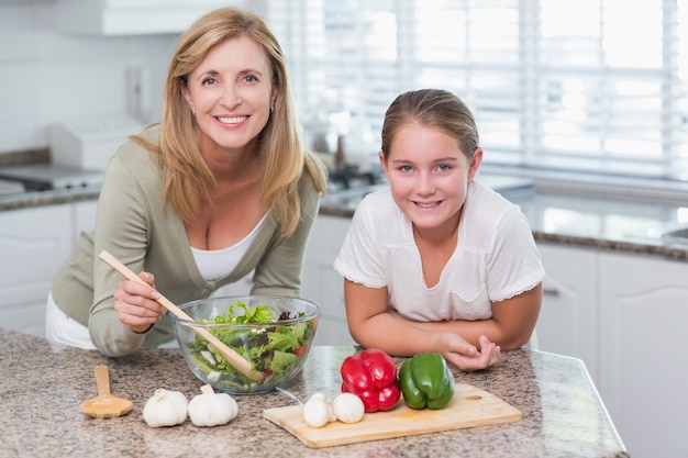 Feliz mãe e filha preparando salada juntos