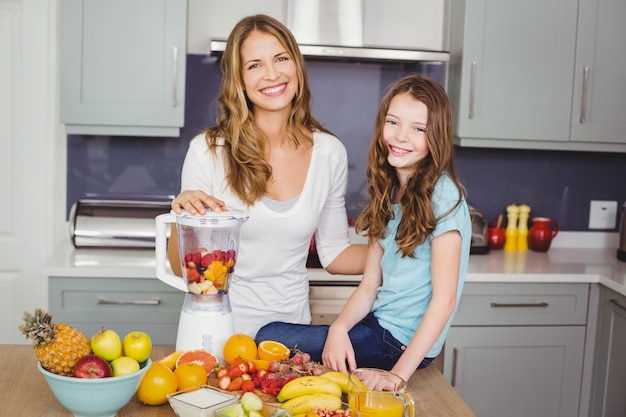 Feliz mãe e filha preparando um suco de frutas
