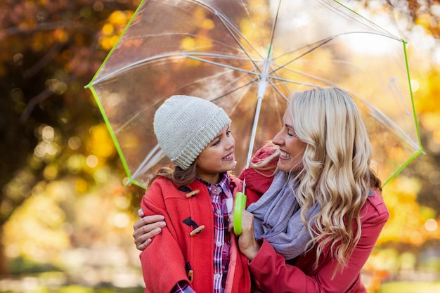Feliz mãe e filha segurando guarda-chuva no parque