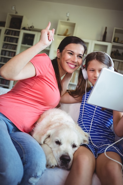 Feliz mãe e filha sentada com cachorro de estimação e usando digital