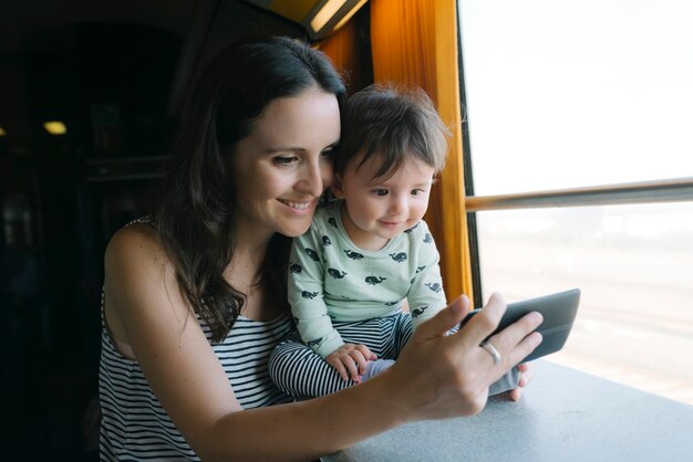 Feliz mãe e filha usando smartphone enquanto viaja de trem