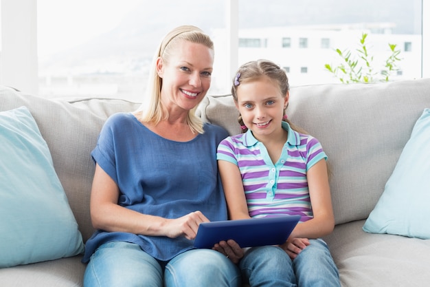 Feliz mãe e filha usando tablet digital no sofá