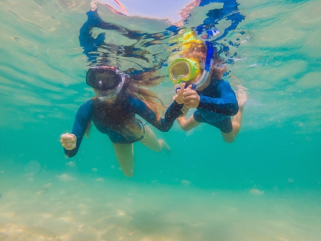 Feliz mãe e filho mergulhando no mar Olhe para os peixes debaixo d'água