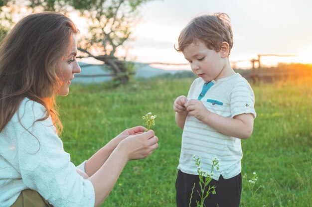 Feliz mãe e filho na natureza no pôr do sol