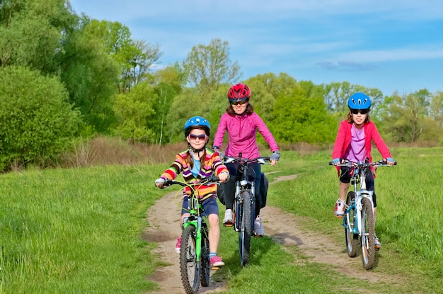 Feliz mãe e filhos em bicicletas andando de bicicleta ao ar livre no parque, esportes familiares ativos e fitness juntos