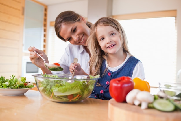 Feliz mãe e sua filha preparando uma salada