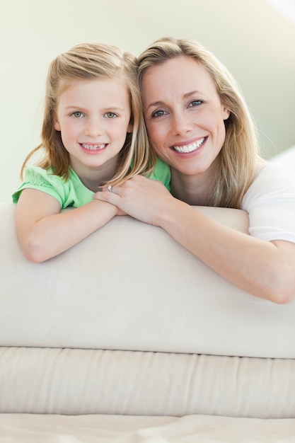 Feliz mãe sorridente e filha no sofá