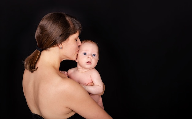 Feliz mamá besando a la madre del bebé besando a su adorable bebé infantil