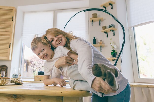 Feliz mamá e hijo se ríen descansando en casa.