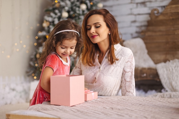 Feliz mamá con niño mirando dentro de la mágica caja de regalo de Navidad