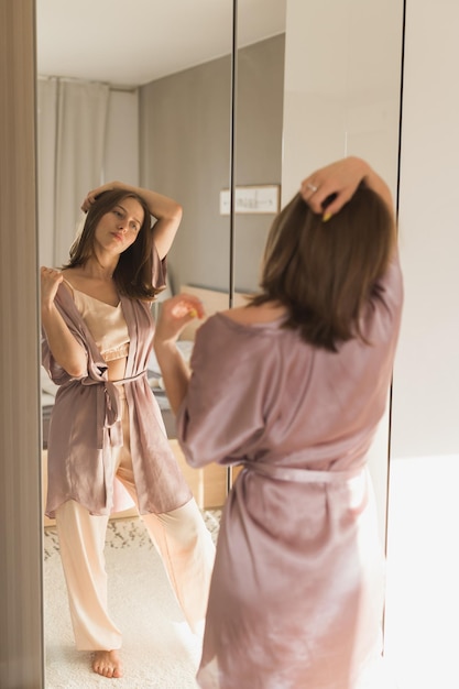 Foto feliz manhã jovem atraente olhando no espelho em seu apartamento