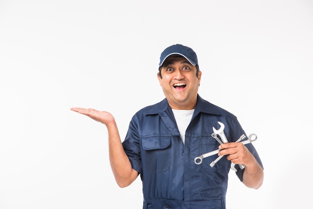Feliz mecánico indio en traje azul y gorra sosteniendo la herramienta llave
