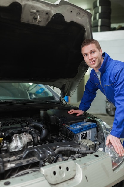 Foto feliz mecánico reparación de motor de automóvil