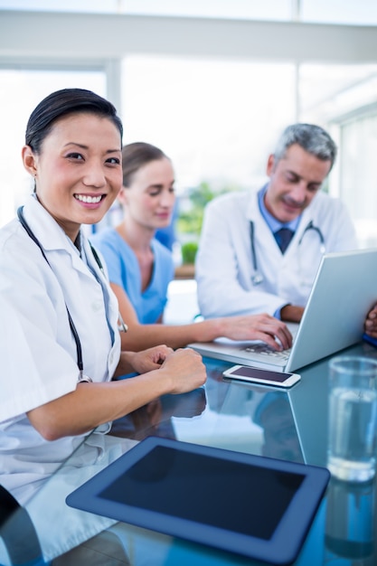 Feliz médico olhando a câmera enquanto os colegas estão falando