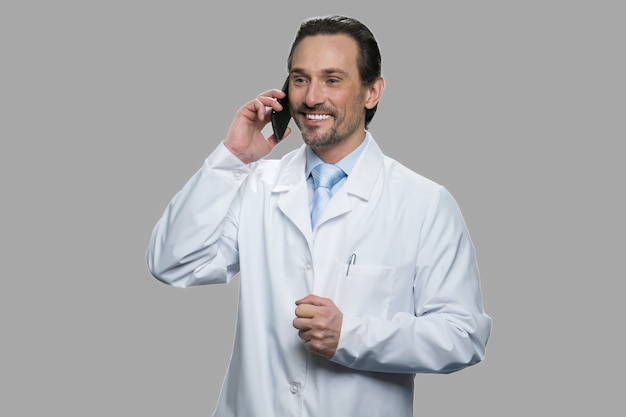 Feliz médico ou cientista falando no celular. Engenheiro de ciências masculino falando no celular contra um fundo cinza.